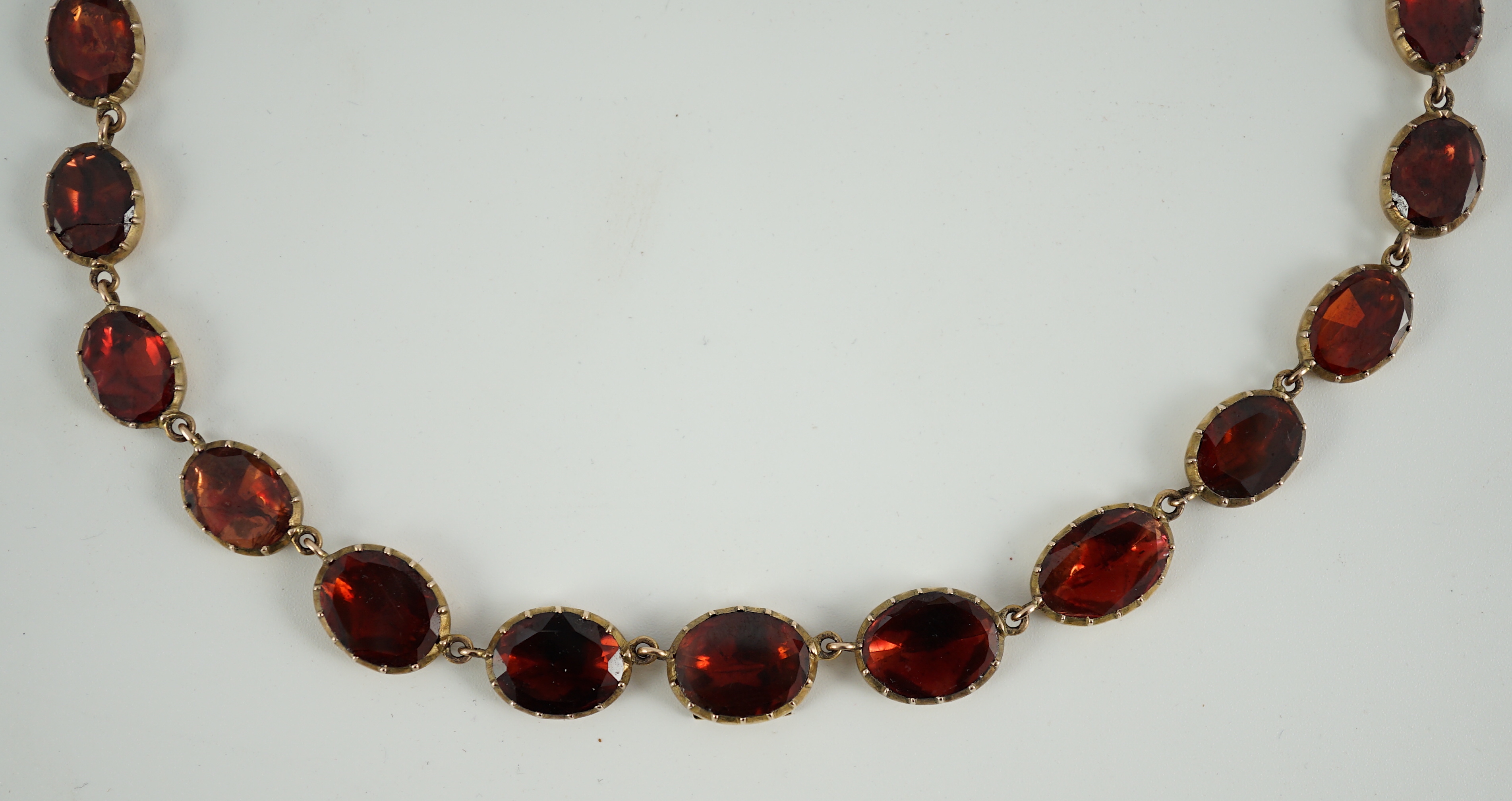 An early 19th century gold mounted graduated foil backed oval cut garnet set choker necklace